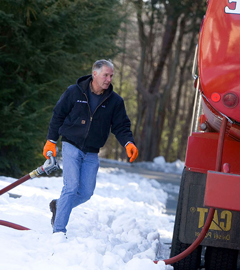Technician running through snow to make a same-day heating oil delivery in Hauppauge, NY